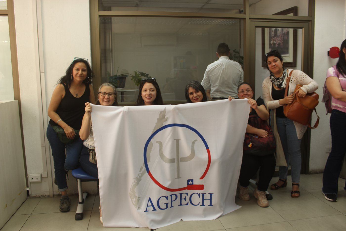 Asociadas y asociados de AGPECH con la bandera del gremio